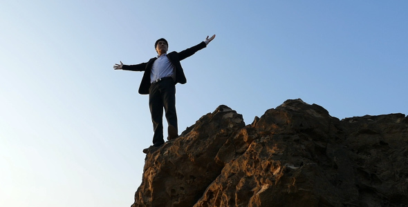 Businessman On Cliff With Arms Outstretched