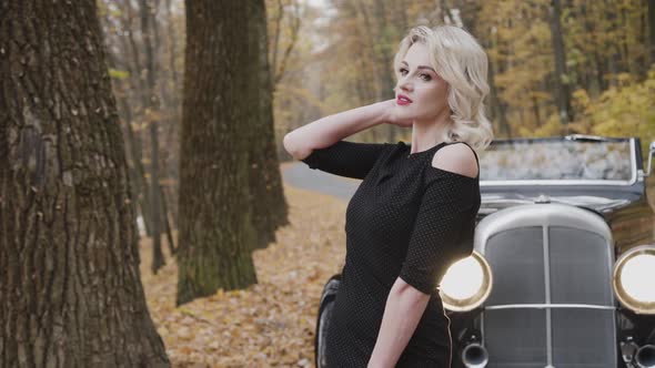 Beautiful Blonde Poses at Retro Cabriolet in Autumn Park