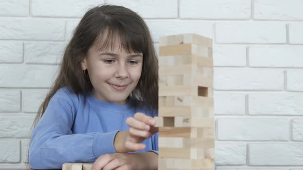 The child collapses the tower of wooden blocks.