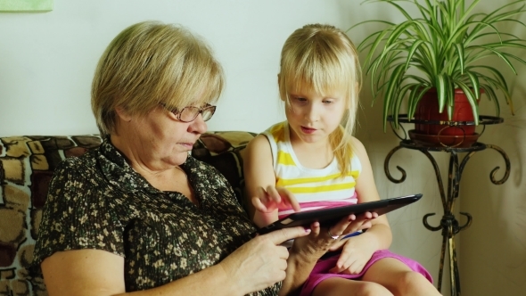 Granddaughter And Grandmother Playing On The Tablet