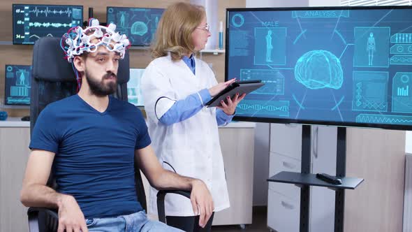 Female Neurologist Reading Data From Brainwave Scanning Headset