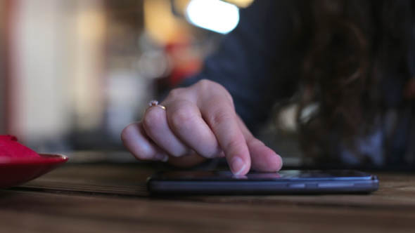 Woman in Cafe Using Phone alt