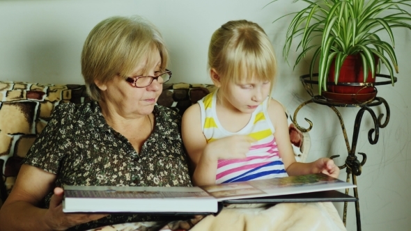 A Girl With Her Grandmother Looking Photo Album