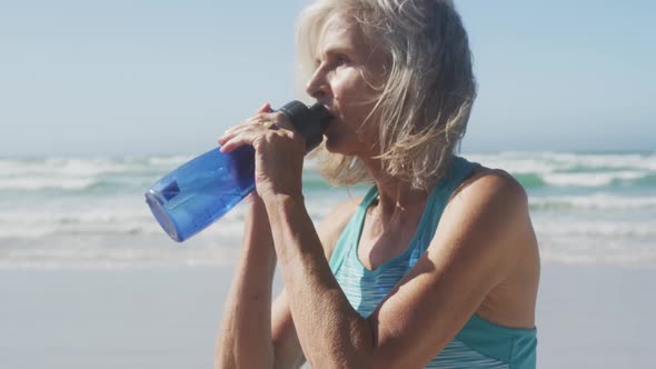 Senior woman drinking water on the beach