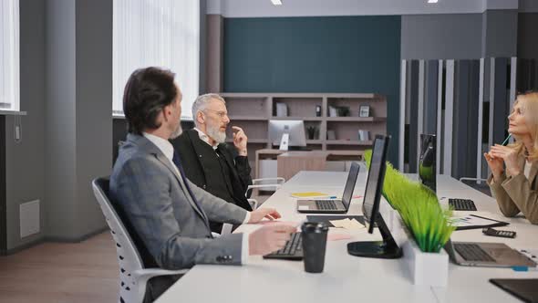 Group of Mature Ceo Partners Discussing Partnership Detail Brainstorming Together at Modern Office