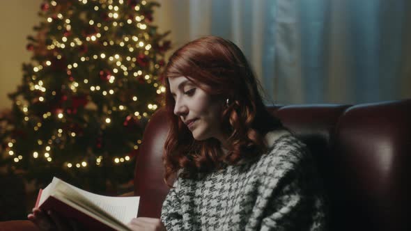 Girl reads book on the sofa at Christmas