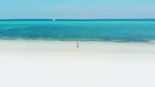 Aerial slow motion: woman walking on white sand tropical beach turquoise water c