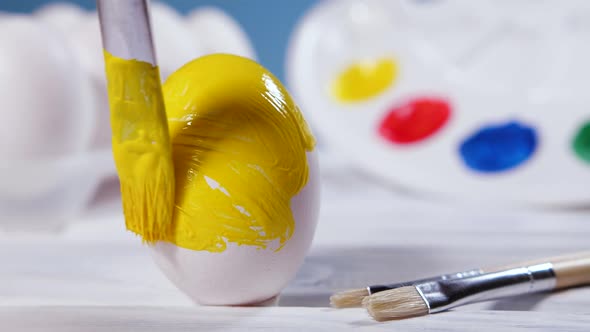 Painting Easter Eggs with a Yellow Brush Preparation for Spring Holiday Religious Celebration Art