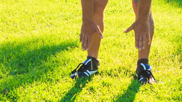 Man Does Morning Exercises Bends to Feet on Green Grass Lawn