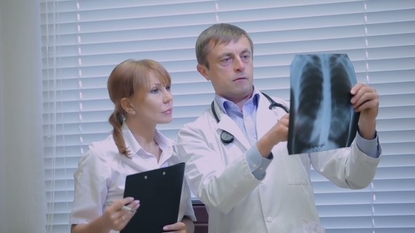 Two Doctors Examining Patients X-rays In Hospital alt