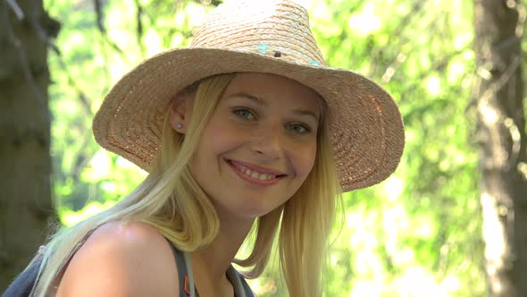 A Young Beautiful Woman Smiles at the Camera in a Forest - Closeup