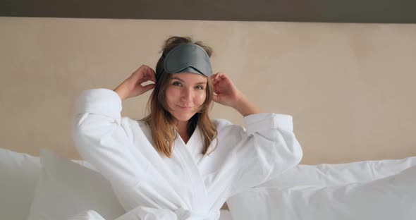 Woman in Bathrobe Adjusts Mask Lying on Comfortable Bed