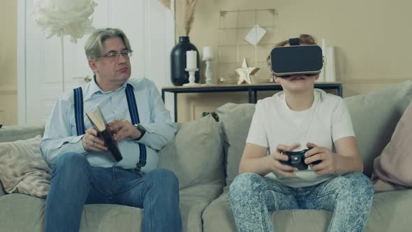 A Boy Is Playing in VR-glasses While His Granddad Is Looking at Him