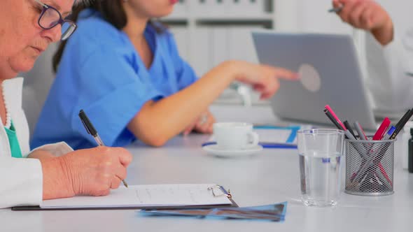 Close Up of Elderly Woman Medic Taking Notes on Clipboard