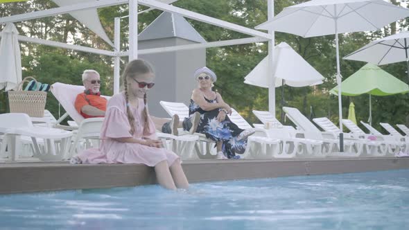 Old Couple Lying on Sunbeds Near the Pool on the Background