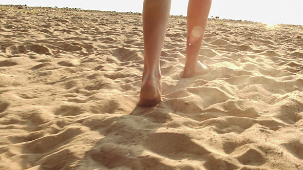 Woman`s Legs In The Beach Sand