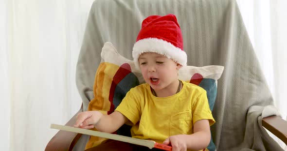 Little Boy in Red Christmas Hat Reads Orange Book Cover