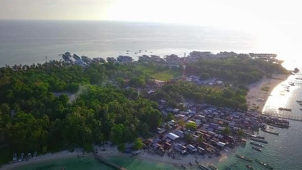 Aerial flight towards forest and village on island in Malaysia, wide distance shot moving forward in