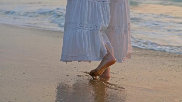 Woman Wearing Lacy White Skirt Slowly Walking Barefoot the Wet Sandy Beach. Waves of the Sea Washing