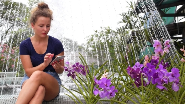 Young Pretty Girl Using Mobile Phone In Summer Park. 