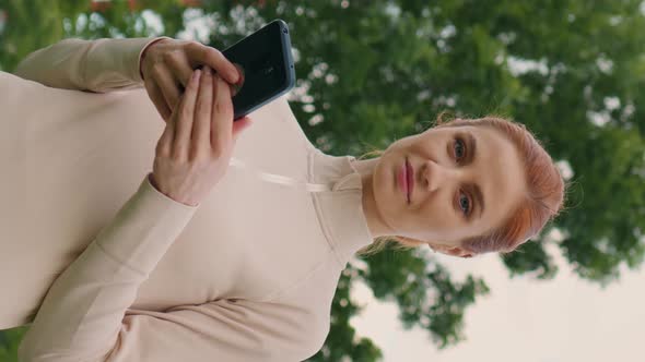 Vertical Screen Portrait woman holding mobile phone while morning workout