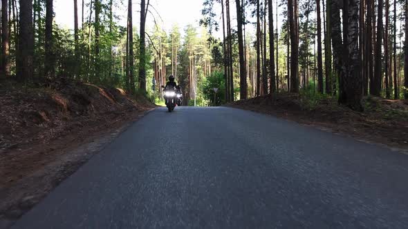 Two Women Riding Motorcycles on the Empty Narrow Road in the Forest