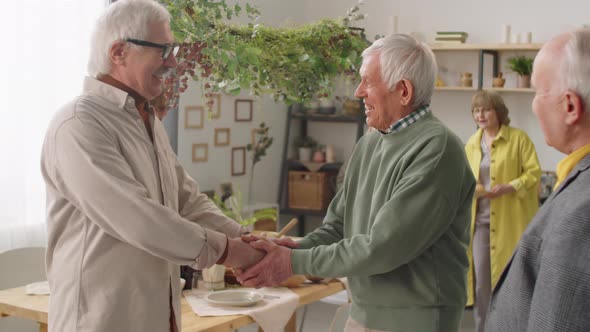 Senior Men Shaking Hands and Talking at Home Party