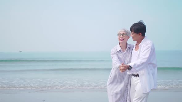 A senior woman dancing with her partner on the beach.