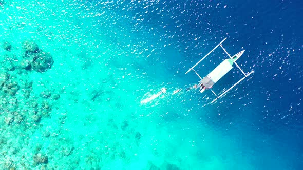 Tourists snorkeling in the aquamarine seawaters near the boat over the coral reef