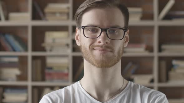 Slowmo Close-up of Smiling Caucasian Man in Eyeglasses Raising Eyebrow. Portrait of Young Bearded