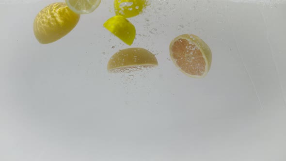 Sectioned grapefruits and lemons dropped into water, Ultra Slow Motion alt