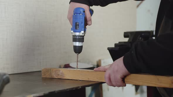 Male Artisan Cuts Piece From Wooden Bar Using Grinder to Which Circular Blade is Attached Closeup