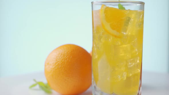 Rotating of Glass with Summer Healthy Lemonade, Cocktail of Orange, Ice and Mint.