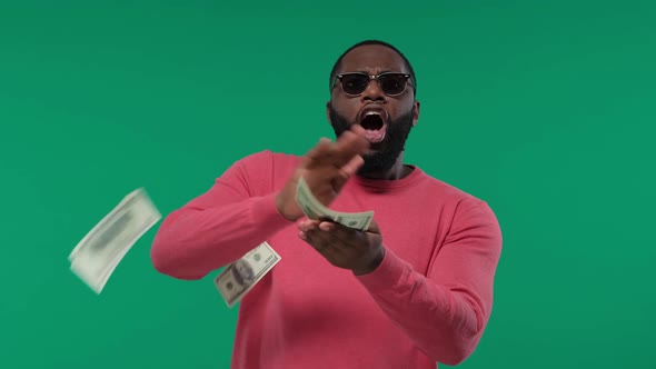 Happy African-American Man Throwing Dollars Banknotes, Wasting Money, on Green Screen, Chroma Key