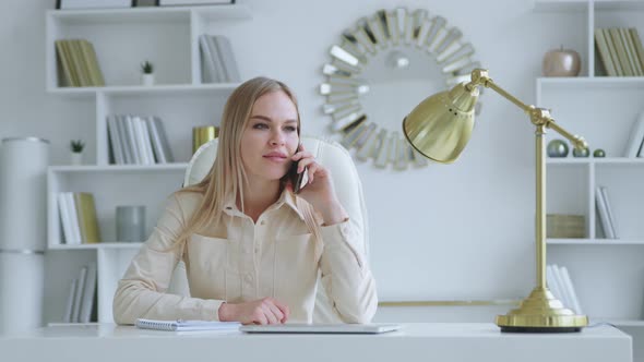 Working woman at home office. Young woman talking on the phone in a room