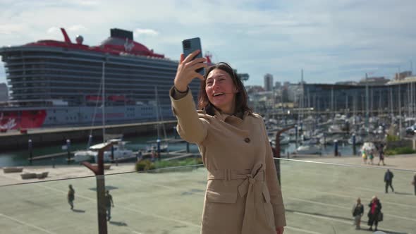 The Girl Takes a Photo of Herself on Her Phone in Front of a Cruise Ship