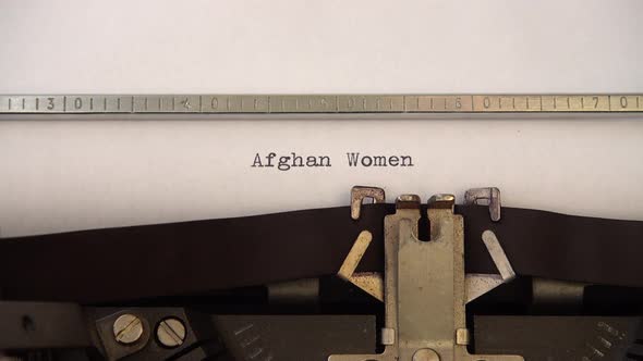 Typing phrase Afghan Women on retro typewriter. Close up.