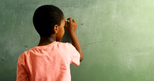 Schoolboy doing mathematics on chalkboard in classroom 4k