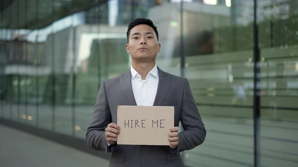 Left To Right Pan Real Time Shot of a Young Asian Man in a Suit Standing on the Street with a Sign