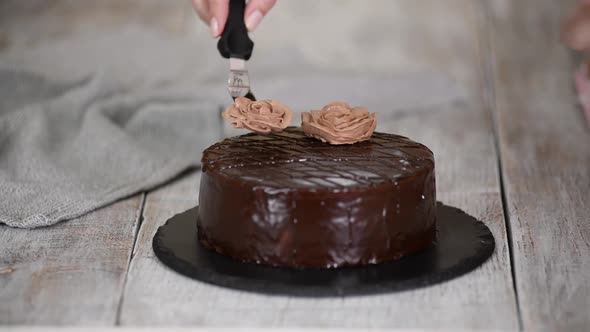 Woman Pastry Chef Decorating a Cake with a Cream Flowers