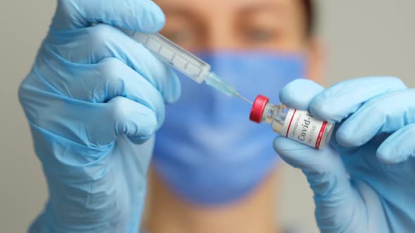 Female Doctor Holds Syringe and Coronavirus Vaccine Vial