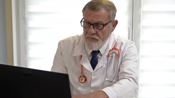 Online Doctor. An Experienced Doctor Consults a Patient Using the Laptop. Covid-19 Epidemic.