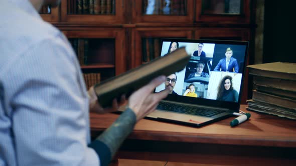 A Man is Showing an Old Book to Online Students During a Lesson