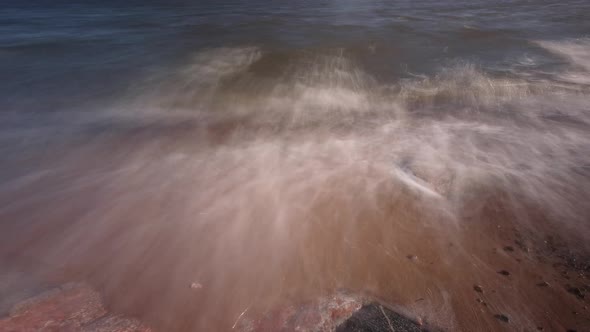 Time-lapse seashore close up with rocks backlit