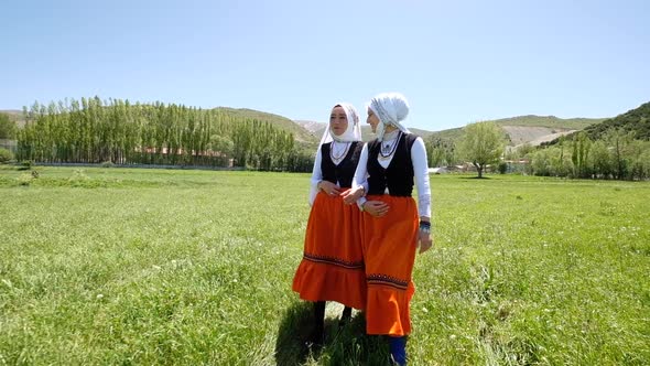 Women In Traditional Dress Talking And Walking In The Meadow In The Village