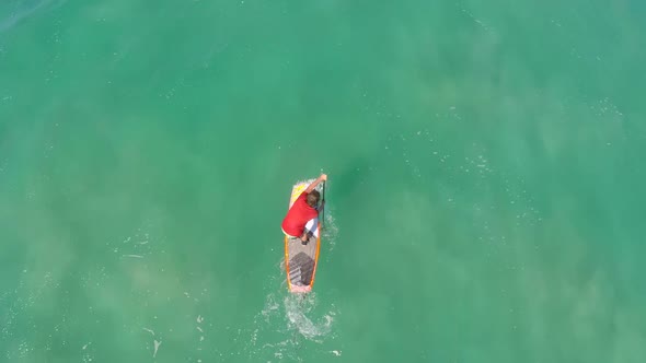 Aerial view of a man sup stand-up paddleboard surfing in Hawaii.