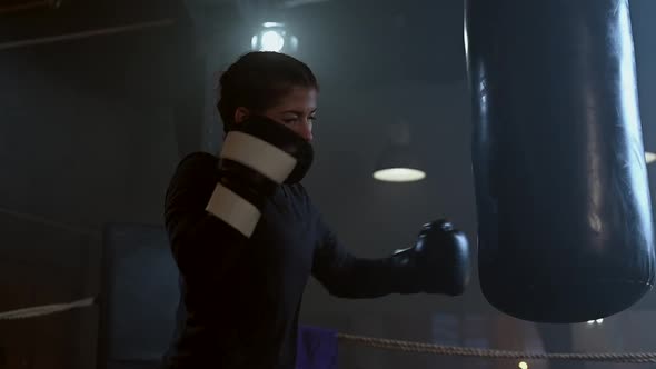 Female Boxer Training in the Dark Ring