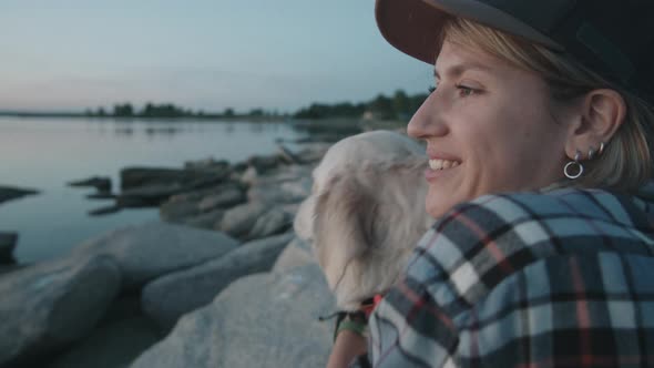Smiling Woman Hugging Cute Dog by Lake