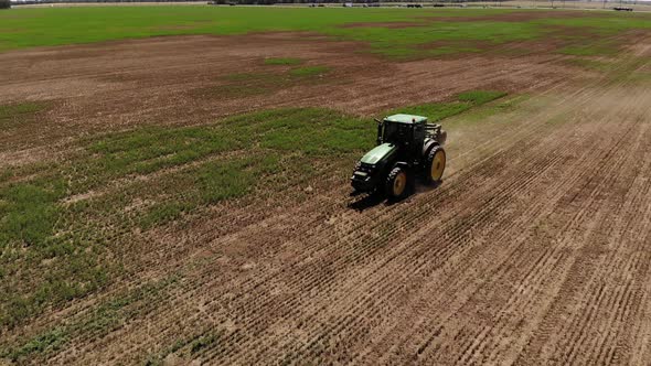 Aerial View of a Tractor with a Mower Mows the Grass on an Empty Field. Field Preparation and