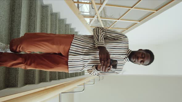Afro Man Standing on Staircase and Using Phone